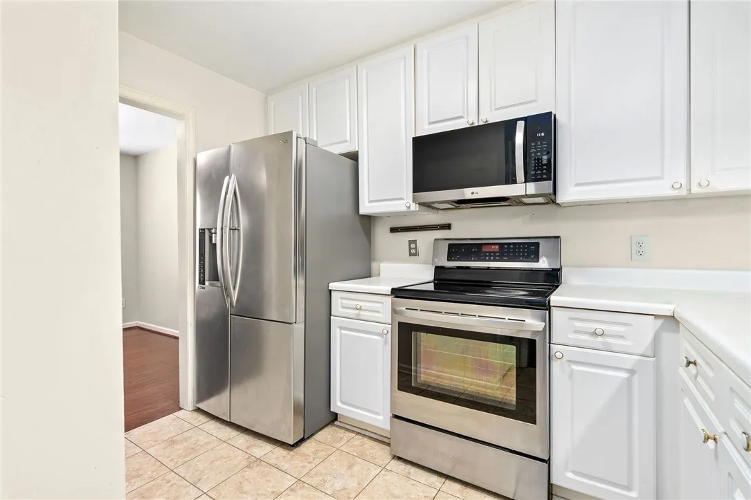 A streamlined kitchen showcasing stainless steel appliances and white cabinetry.