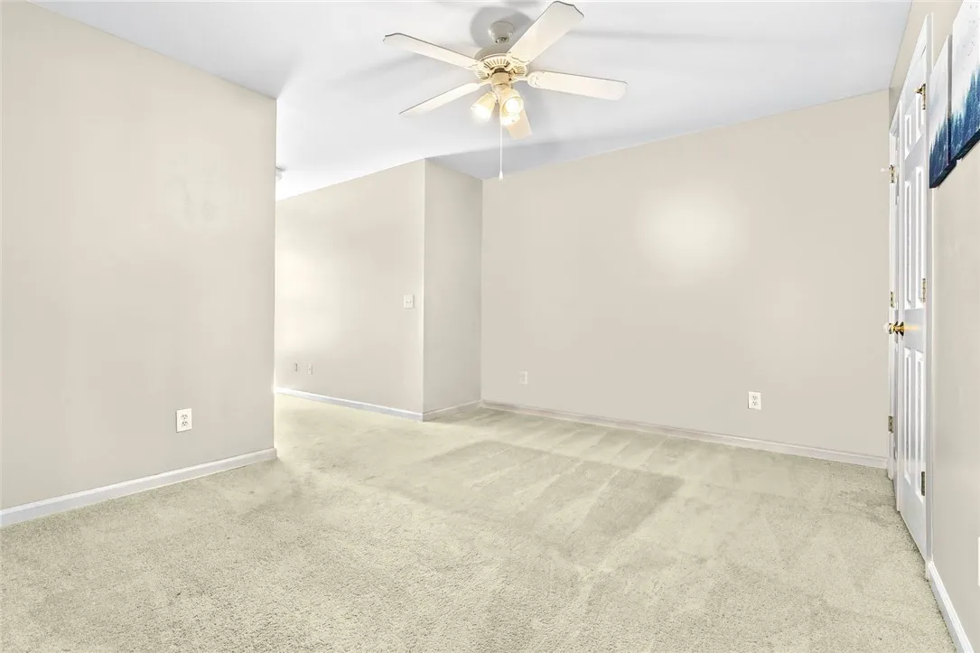 A spacious room offers comfortable carpeting and a cooling ceiling fan.