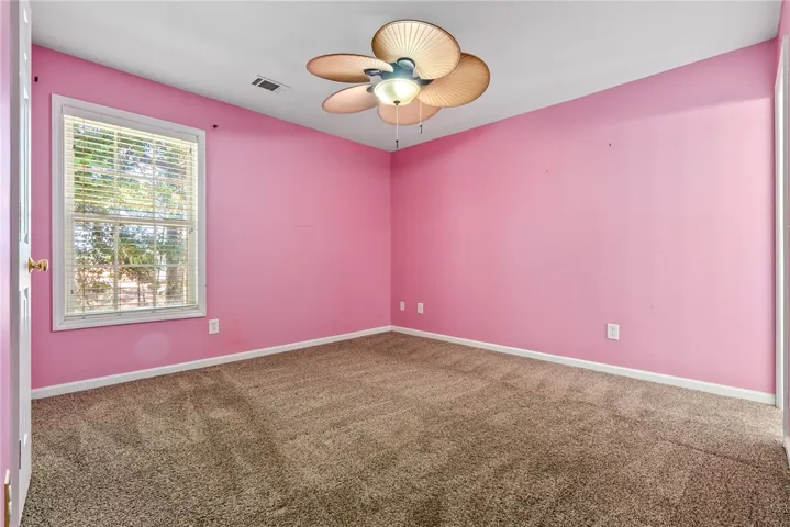 This cozy bedroom features soft carpeting and a window with blinds, creating a comfortable and inviting atmosphere.