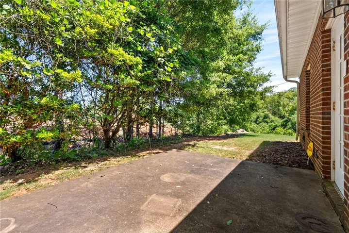 This concrete patio offers a serene outdoor space, perfect for relaxing amidst lush greenery.