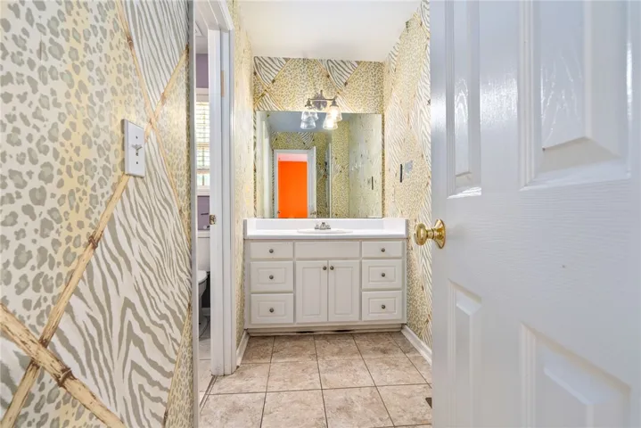 This powder room features a classic vanity and tile flooring, perfect for a quick refresh.