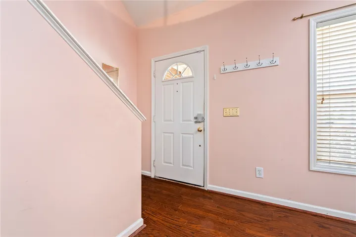 The inviting entryway features a sturdy door, rich hardwood floors, and a bright window.