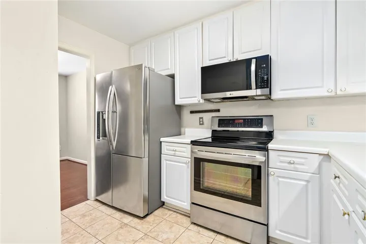 A streamlined kitchen showcasing stainless steel appliances and white cabinetry.