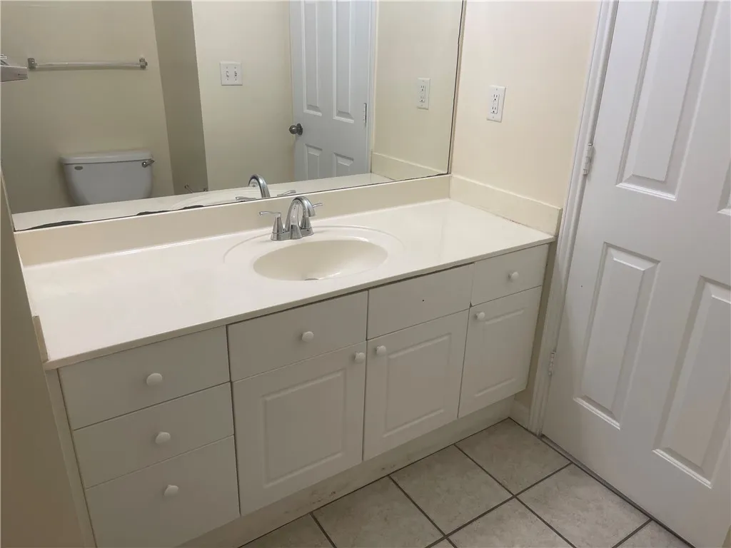 This bright bathroom offers a single vanity with ample storage and tiled flooring.