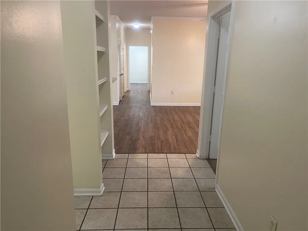This interior hallway features charming built-in shelving, tile and wood flooring, and bright recessed lighting.