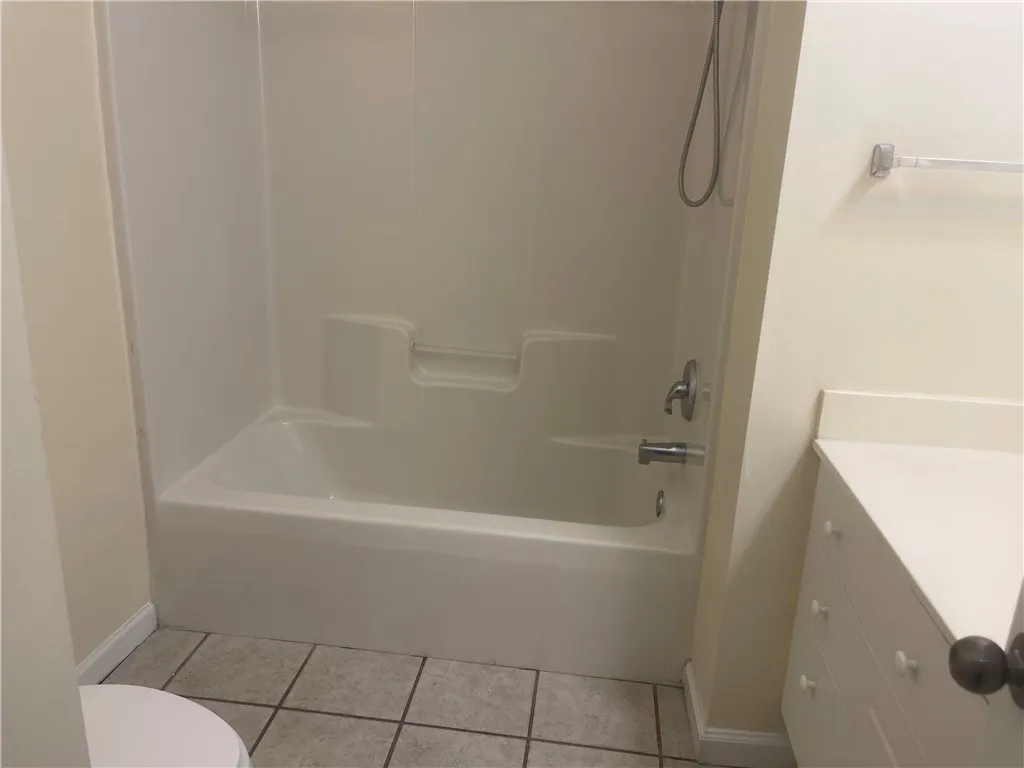 This bathroom features a sleek tub and shower combination with practical tile flooring.
