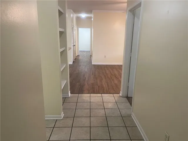 This interior hallway features charming built-in shelving, tile and wood flooring, and bright recessed lighting.