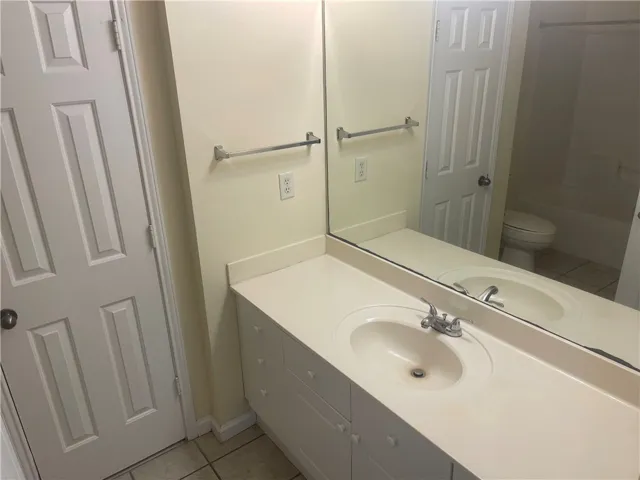 This bathroom features a functional vanity, an integrated sink, and a large mirror.