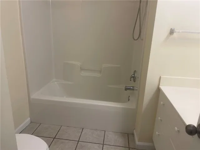 This bathroom features a sleek tub and shower combination with practical tile flooring.