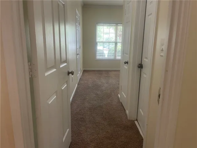 This interior hallway features neutral tones and leads to a bright window, creating a welcoming passage.