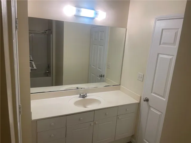 This bathroom features a sleek vanity and a spacious mirror, offering both style and utility.
