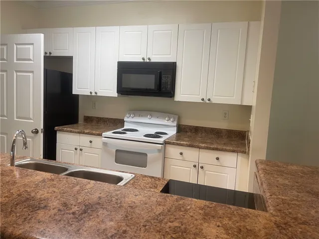 This modern kitchen features crisp white cabinetry, a functional sink, and integrated appliances for comfortable living.