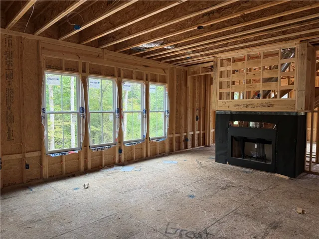 Exposed framing reveals the structural design of a living room featuring a central fireplace.
