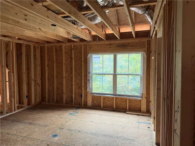 Exposed wood framing and open rafters define this space currently under construction.