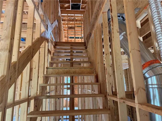 Exposed wood framing reveals the structural skeleton and rising staircase during the construction process.
