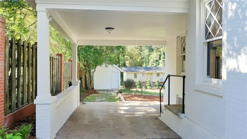 This inviting porch offers a tranquil transition to the verdant yard and storage shed.