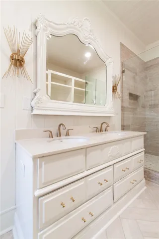 This spacious bathroom features a double vanity and a beautifully tiled shower, offering both comfort and style.
