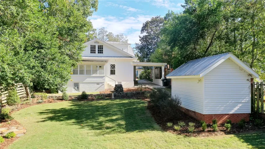 This classic white home features a lush green yard and a charming detached outbuilding.