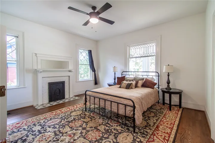 This spacious bedroom features a classic fireplace and gleaming hardwood floors, creating an inviting retreat.