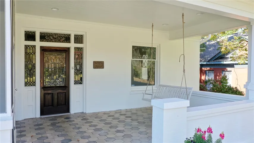 Entertain guests on this welcoming front porch featuring intricate door details and comfortable seating.