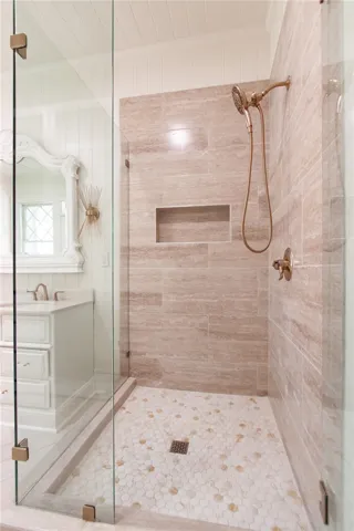 This bathroom features a sleek glass-enclosed shower with sophisticated tile work and a charming vanity.