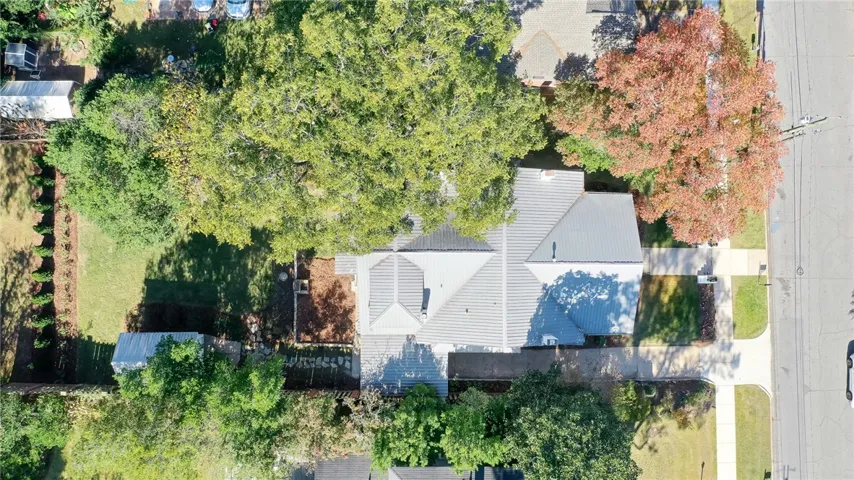An aerial view showcases a residential property nestled amidst lush trees with a metal roof.