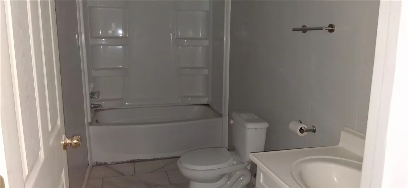 This functional bathroom features a tub, shower, and tile flooring, ready for daily use.