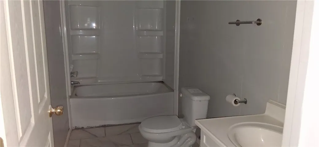 This functional bathroom features a tub, shower, and tile flooring, ready for daily use.