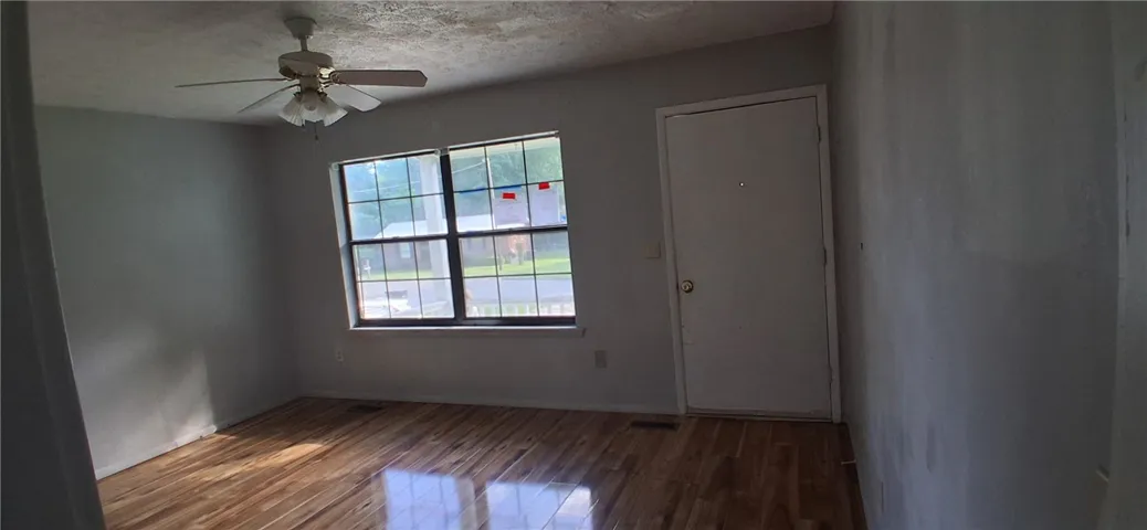 This living area features rich hardwood flooring and a functional ceiling fan.