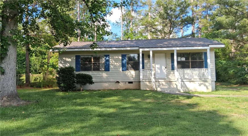 Charming home with welcoming porch and mature trees for natural shade.