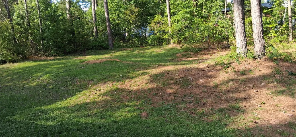 A verdant, gently sloping lawn provides ample space amidst surrounding mature trees.