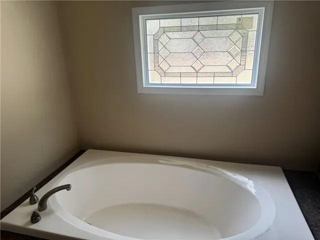 Relax in this inviting tub, illuminated by a patterned window providing privacy and light.
