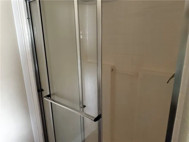 Step into this sleek shower featuring contemporary glass doors and a pristine tiled interior.
