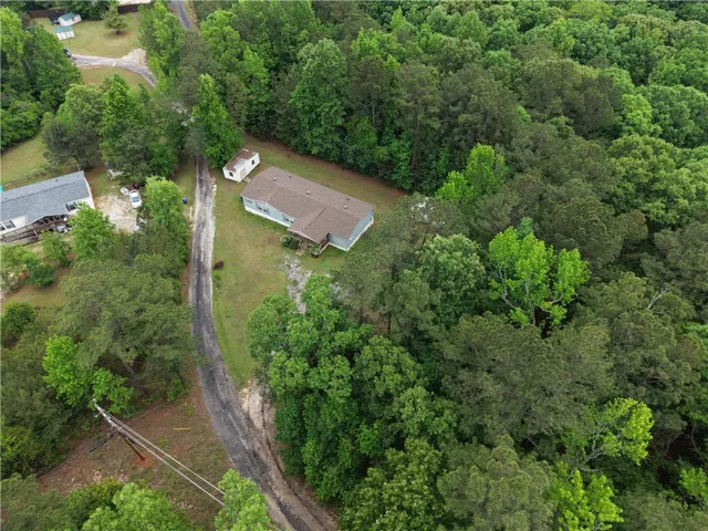 An aerial perspective reveals a secluded residence nestled within a verdant, wooded landscape.