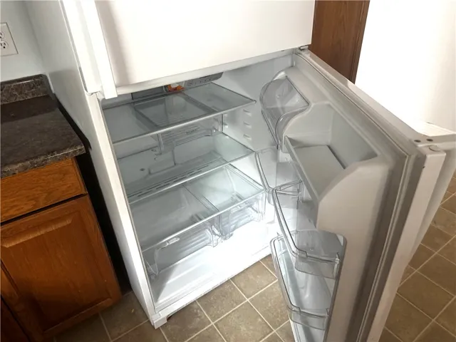 This kitchen showcases a clean refrigerator ready for use, complementing the practical tile flooring.
