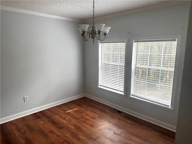 A well-proportioned room with warm wood flooring and abundant natural light from multiple windows.