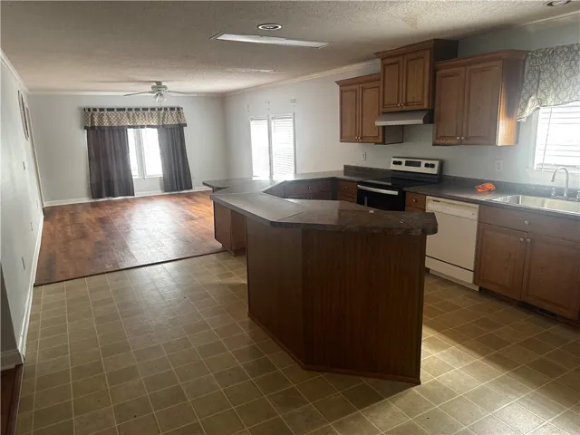 Functional kitchen and living area featuring a central island and warm wood cabinetry.