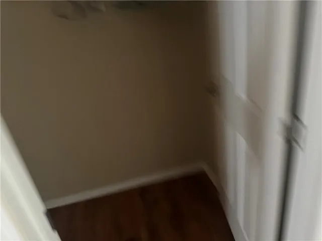 This closet offers ample storage space with rich hardwood flooring.