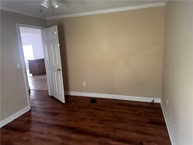 This versatile room features warm flooring, crown molding, and an inviting entryway to adjacent spaces.