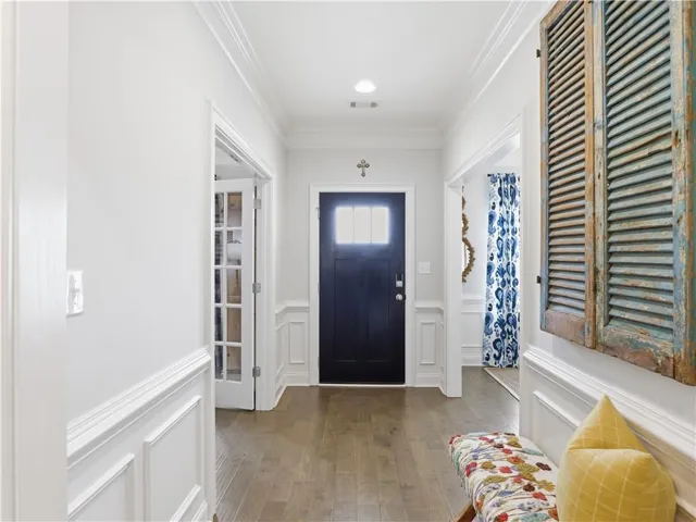 Enter into a welcoming hallway featuring warm hardwood floors and wainscoting.
