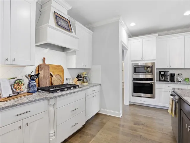 White cabinetry, light granite counters, and a sleek gas range define this functional kitchen.