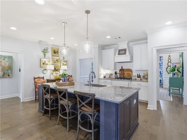 A well-appointed kitchen features an expansive island with granite countertops, hardwood flooring, and contemporary pendant lighting.