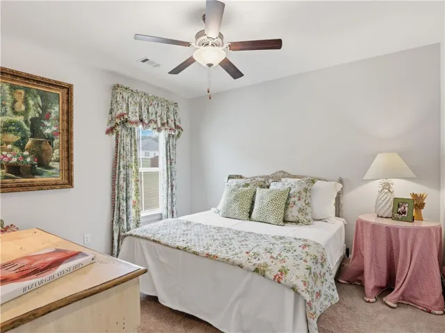 Comfortable bedroom with ample natural light, soft carpet, and a ceiling fan for year-round comfort.