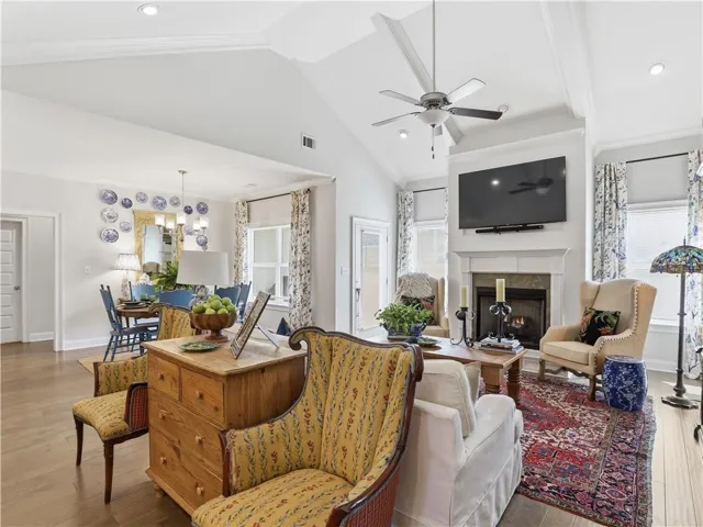 The open-concept living area boasts a fireplace and soaring vaulted ceilings, connecting seamlessly to a sun-filled dining space.