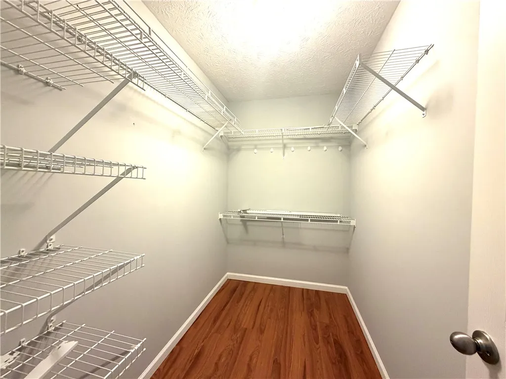 Ample closet space with wire shelving and wood-look flooring offers practical storage solutions.