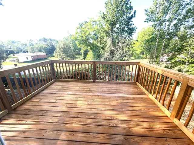 This spacious wooden deck offers an ideal spot for outdoor enjoyment amidst natural surroundings.