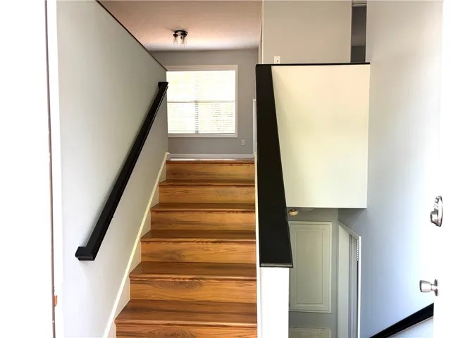 Navigate this inviting interior featuring robust wood stairs with modern dark railings leading to an upper landing.