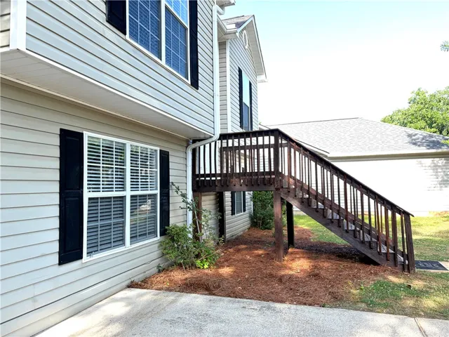 Exterior view showcases the structure's siding and the access to the upper level via an outdoor staircase.