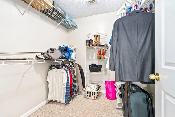 This organized walk-in closet provides ample storage with wire shelving and hanging rods.