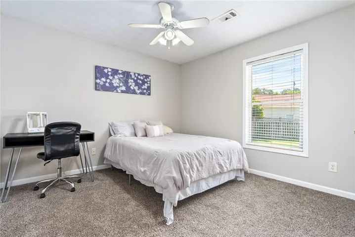 This cozy bedroom features plush carpeting and a large window, creating a serene personal retreat.